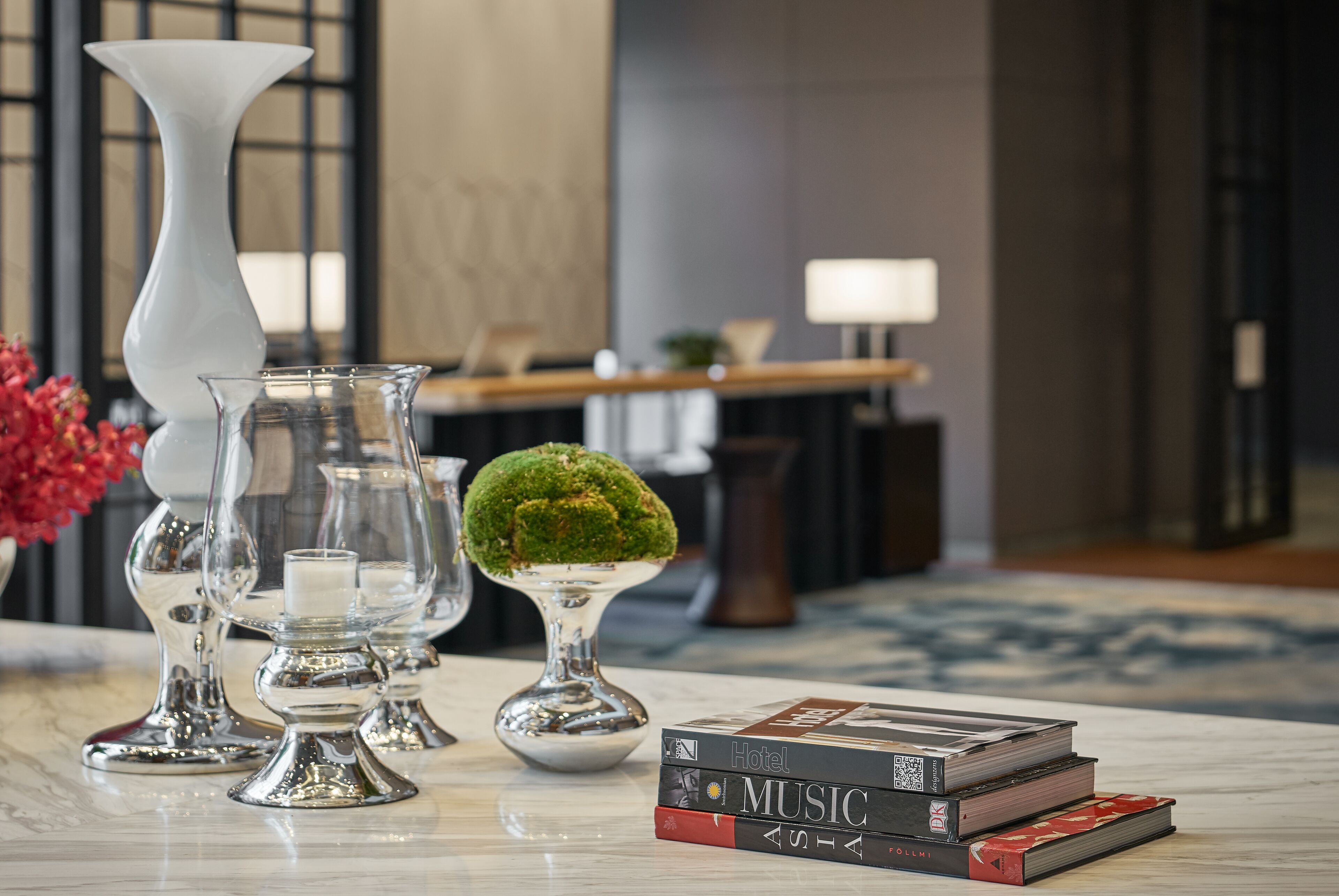 Une table en marbre ornée de vases en verre décoratifs, une petite plante en pot et une pile de livres.