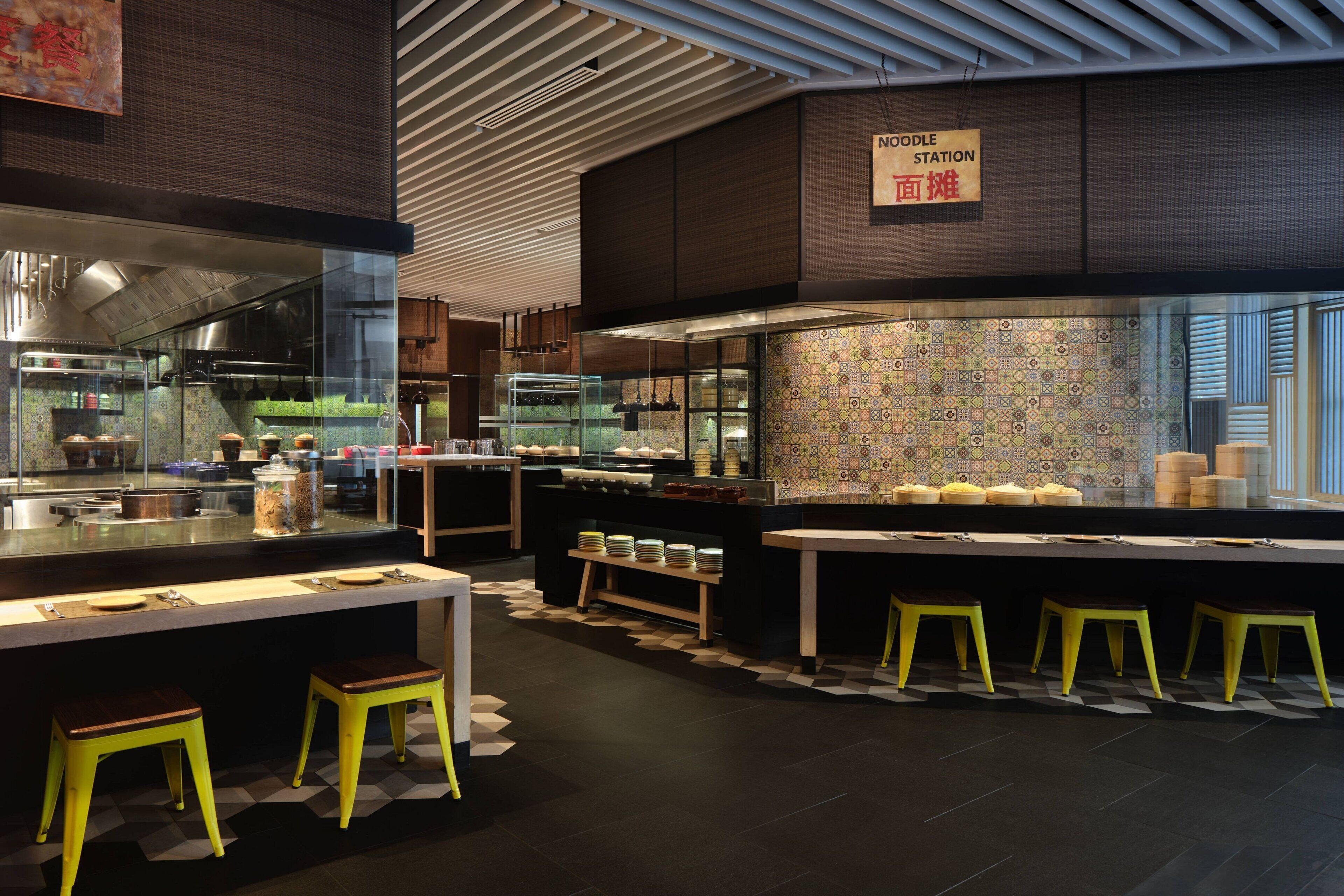 En moderne restaurant med et køkkenområde, en buffet og flere barstole.