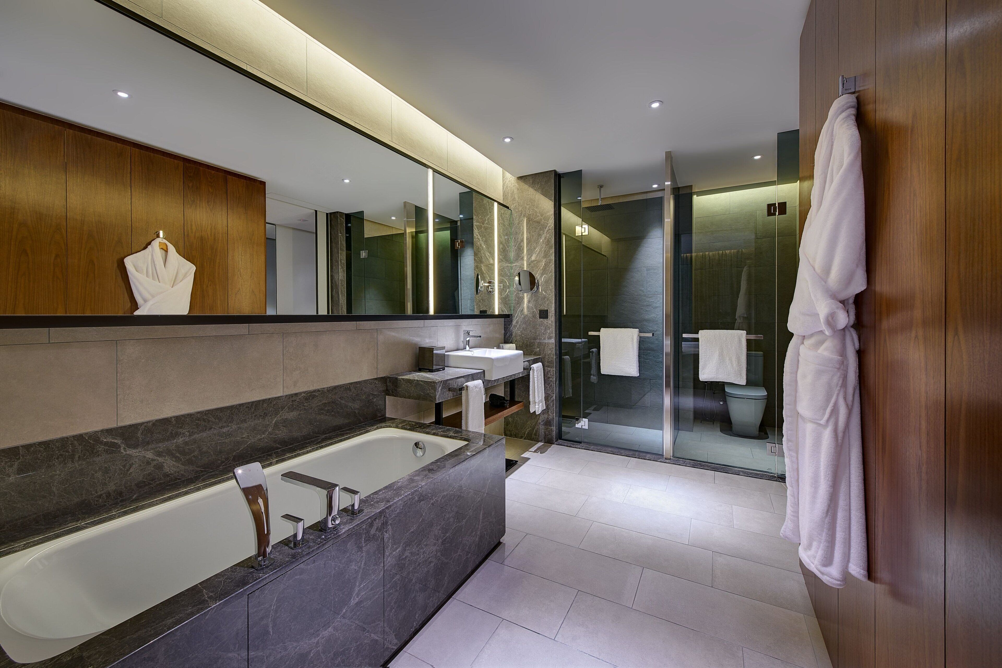 A modern bathroom with a large bathtub, a vanity with a mirror, and a glass shower enclosure.