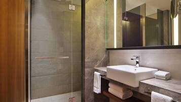Un bagno moderno con doccia vetrata, un ampio specchio e un piano in marmo con lavabo e porta asciugamani.