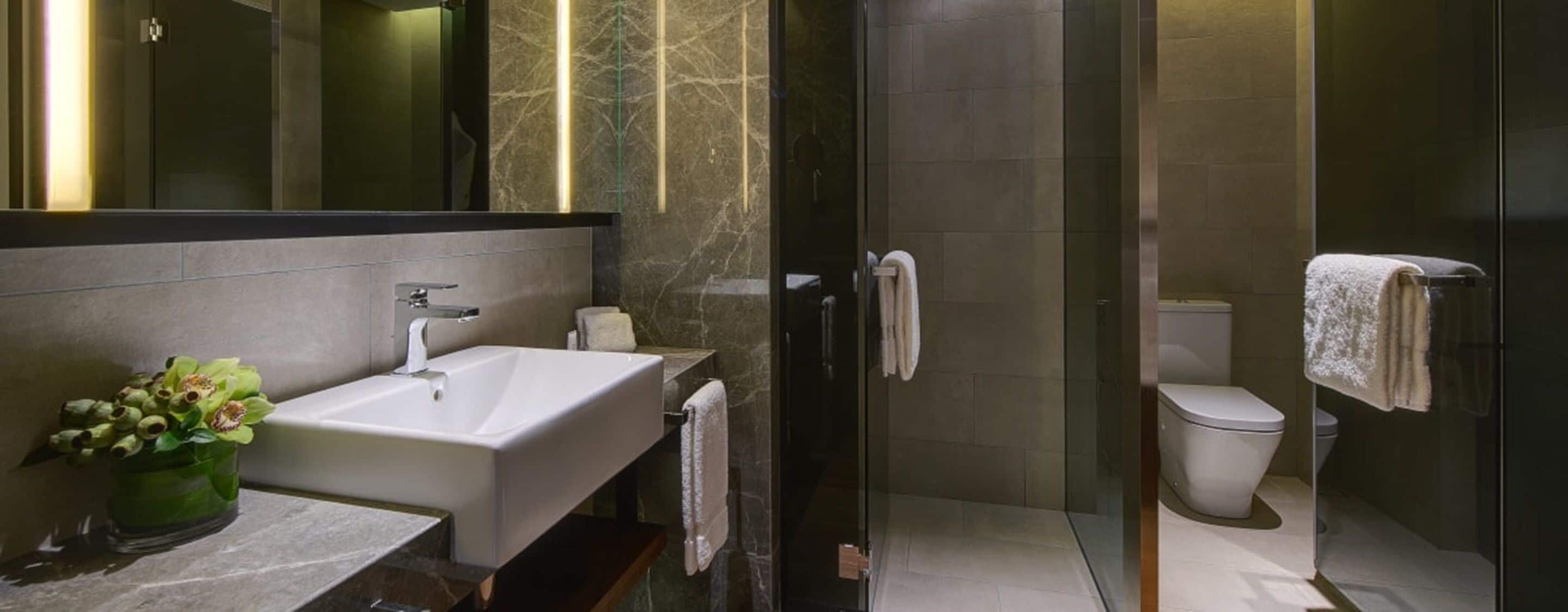Un baño moderno con un lavamanos grande, cabina de ducha de vidrio y un inodoro.