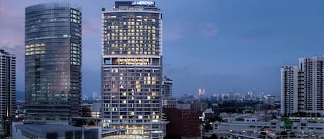 A high-rise hotel with a prominent Meridien sign, surrounded by other buildings and a cityscape at dusk.