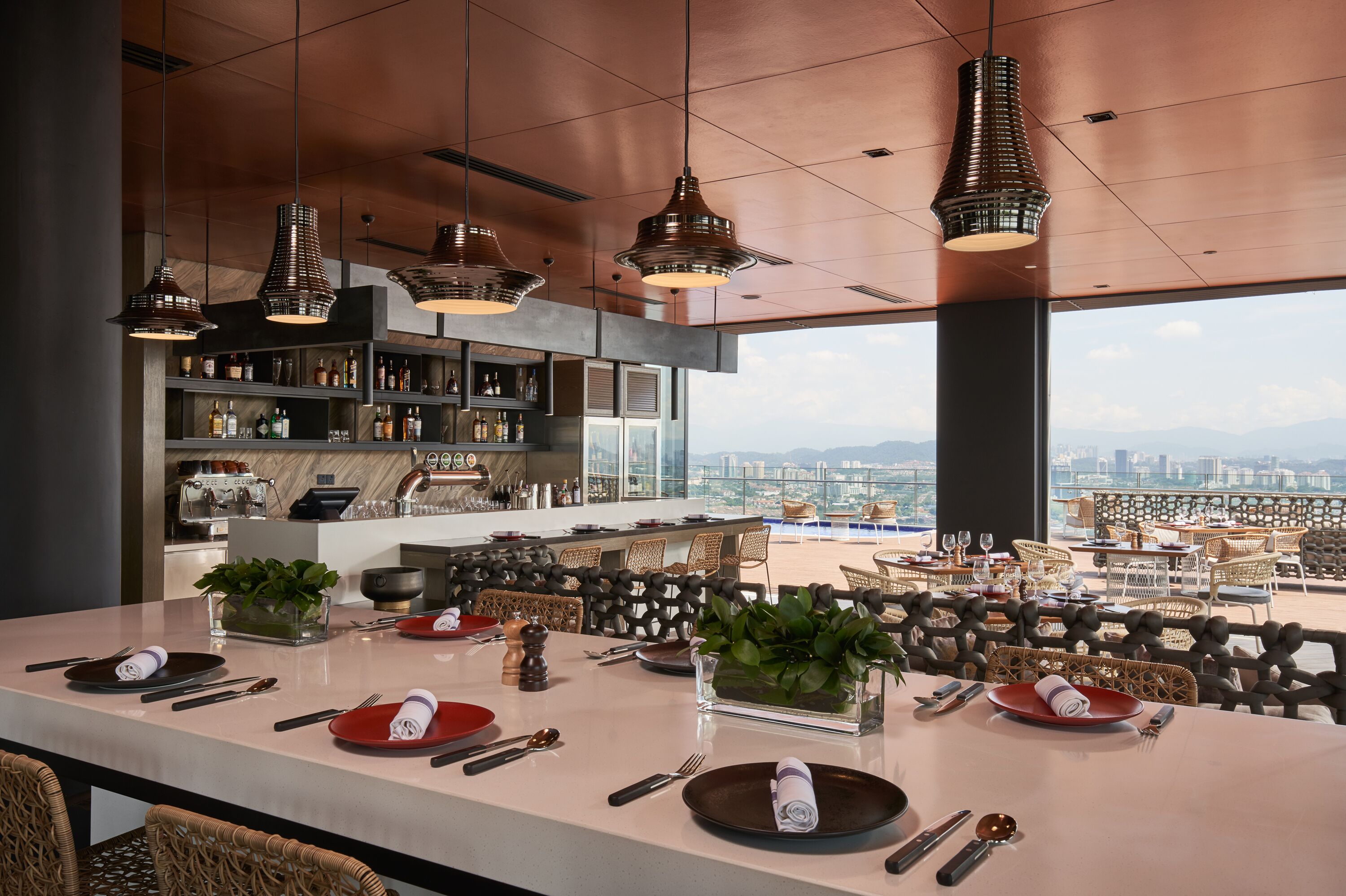 A modern kitchen with a large island, bar area, and seating overlooking a cityscape.