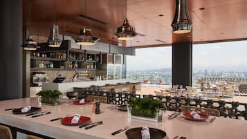 A modern kitchen with a large island, bar area, and seating overlooking a cityscape.