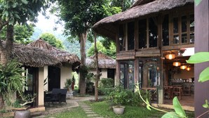 Un bâtiment de style traditionnel, avec des toits de chaume, une cour pavée et des plantes en pot.