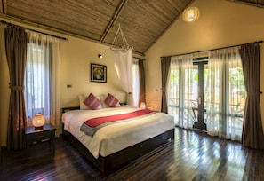 Un dormitorio con una cama grande, suelo de madera, una lámpara colgante y vistas a través de una puerta de cristal.