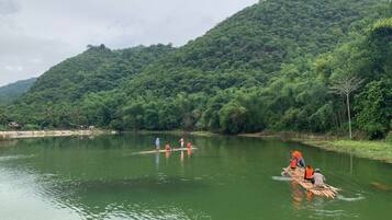 A river with people paddling on wooden rafts.