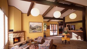 A cozy lobby with a fireplace, patterned armchairs, and a stone floor. - Hakuba Alpine Hotel (Hakuba)