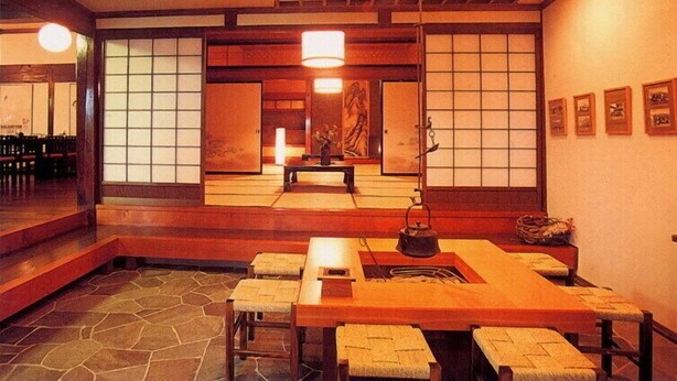 A traditional Japanese room with tatami flooring, a low table with cushions, and sliding doors. - Hakuba Alpine Hotel (Hakuba)