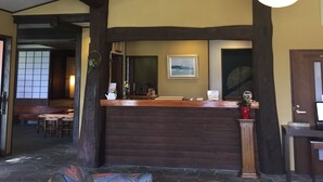 A lobby with a reception desk, patterned sofas, a stone floor, and a high ceiling with exposed beams. - Hakuba Alpine Hotel (Hakuba)