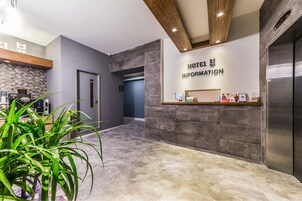 A hotel reception area with a modern design, including a reception desk, a digital information board, and a reception counter.