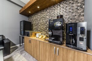 A modern kitchen with a coffee maker, microwave, and refrigerator.
