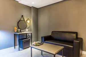 A modern living room with a black leather sofa, a small coffee table, and a side table with a lamp and books.