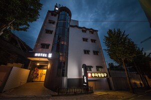 Un hotel de diseño moderno, con un eje de ascensor de vidrio visible e indicación de zona de estacionamiento.