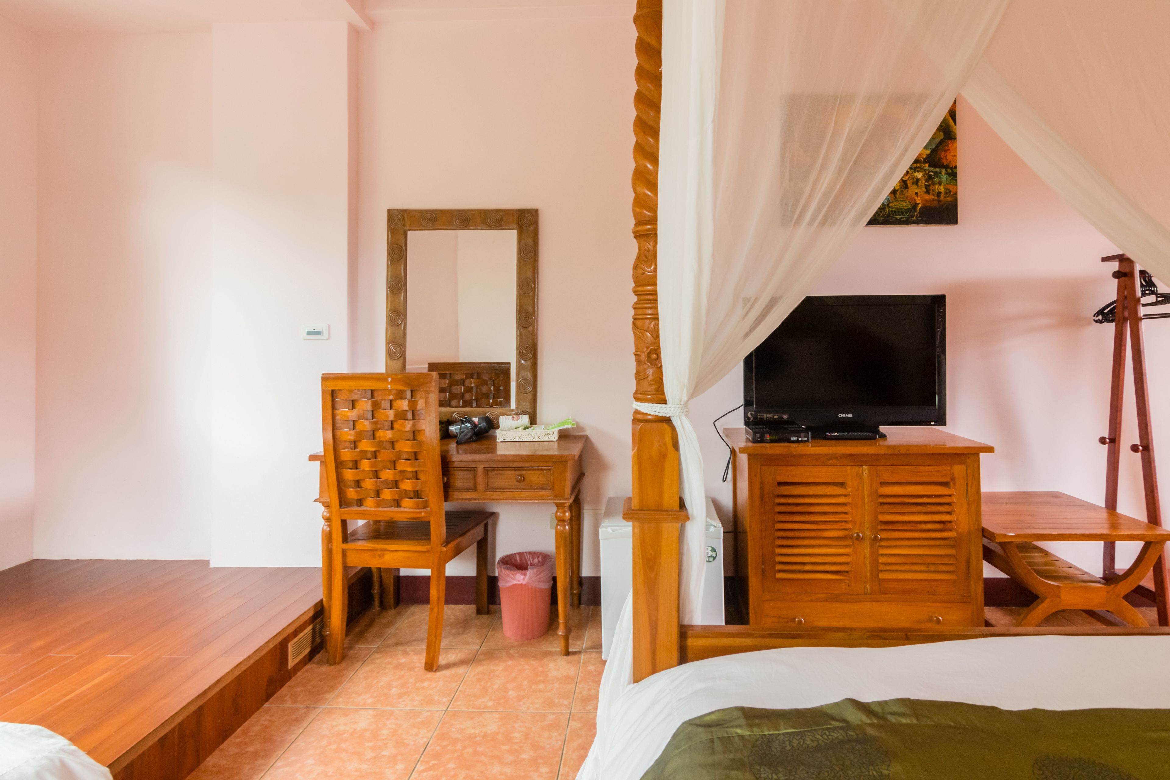 Un dormitorio con una cama, un escritorio con silla, un televisor y un armario.