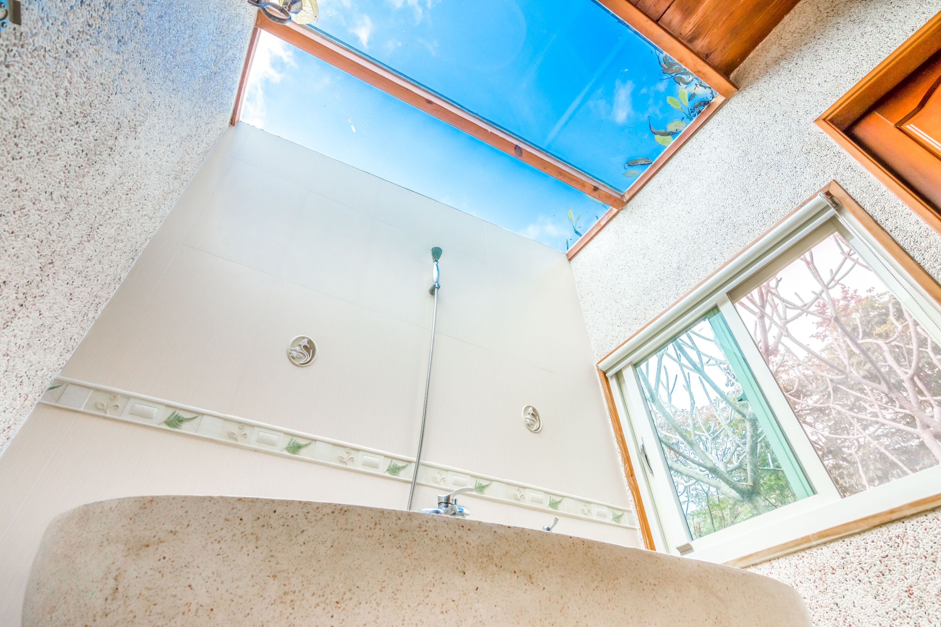 A bathroom with a skylight, a window, and a sink.