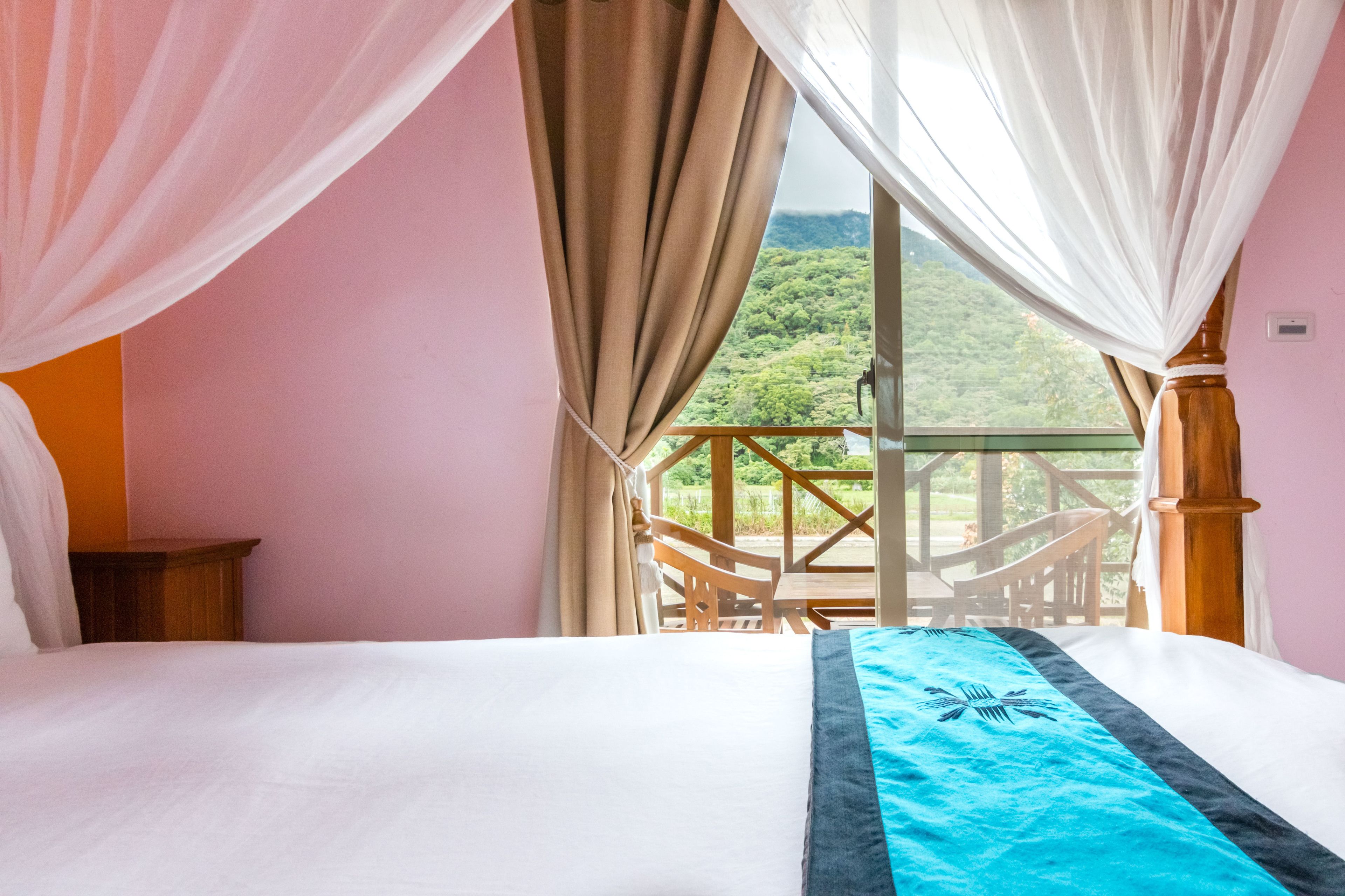 Ein Schlafzimmer mit einem Bett, Balkonblick und einem Holzstuhl.