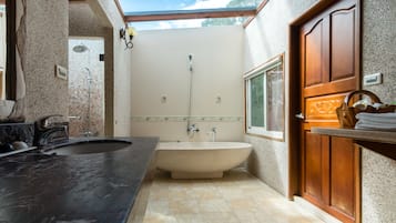 A bathroom with a freestanding bathtub, a sink, and a shower.