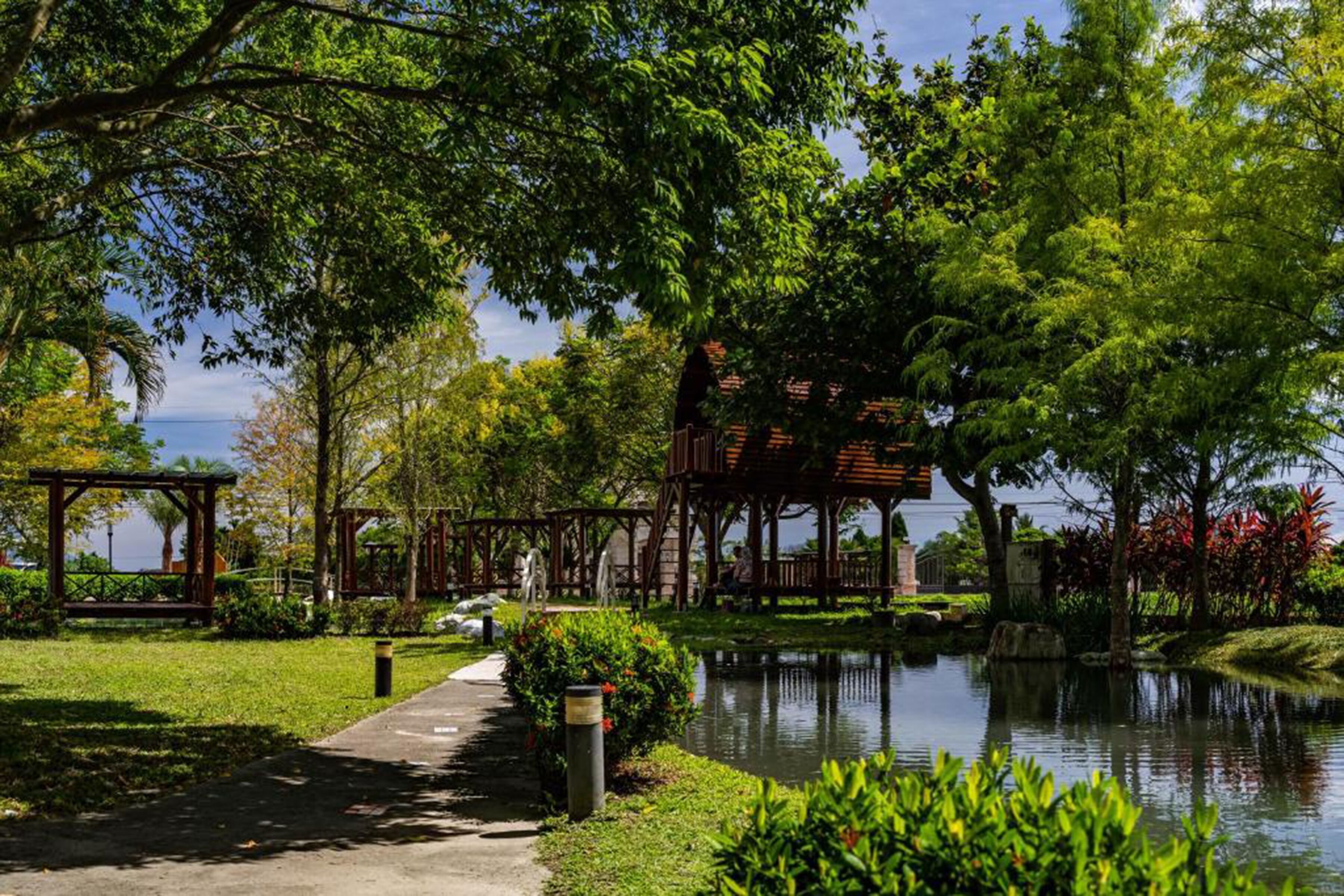 A serene park with a wooden gazebo, a pond, and a pathway.