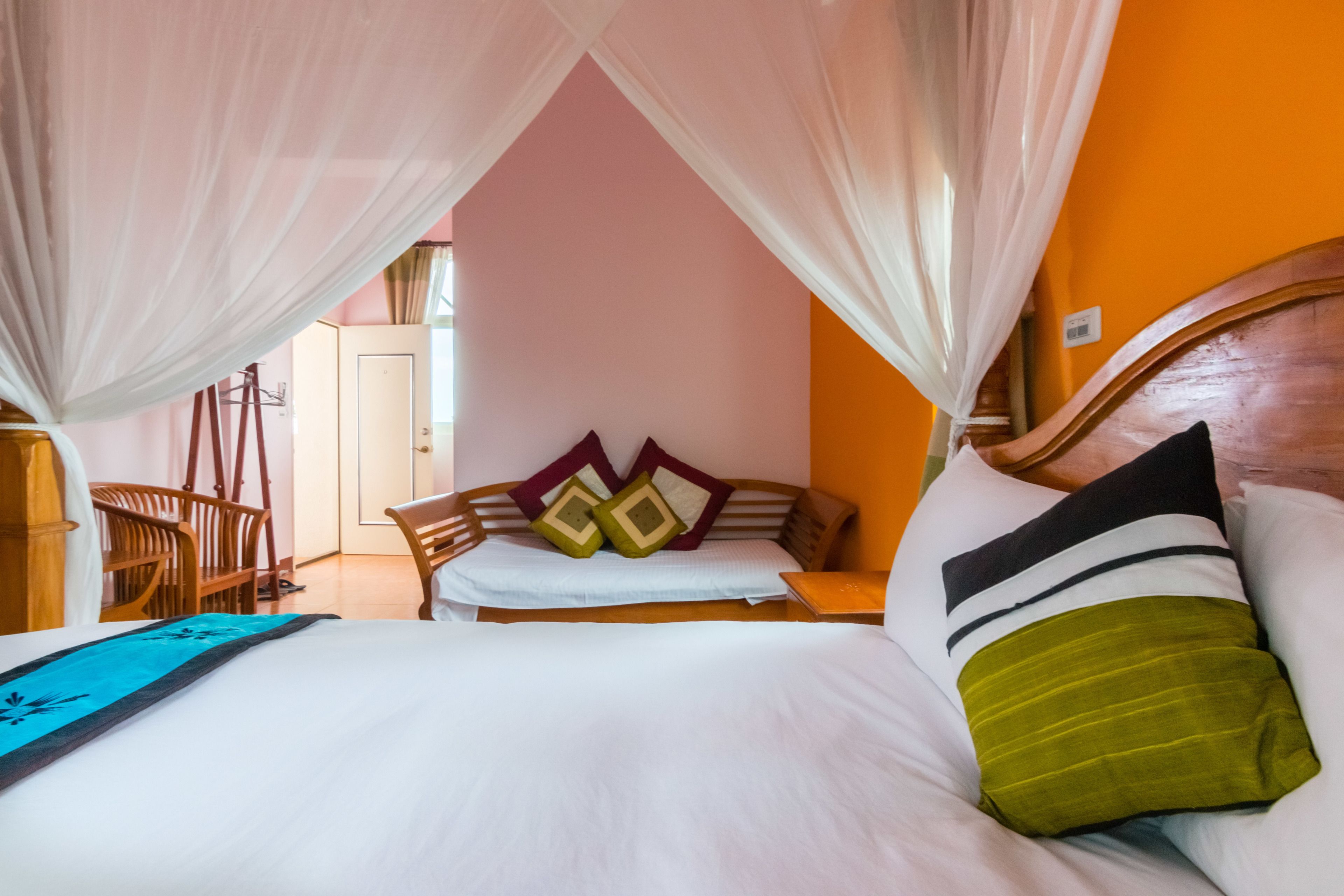 A bedroom with a bed, a wooden headboard, a nightstand, a chair, and a window with curtains.