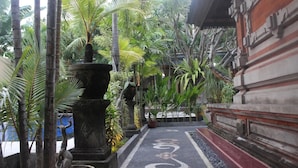 A pathway with a decorative pattern leading to a building with traditional architecture. - Puri Anom Guest House (Denpasar)