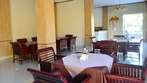 A spacious dining area with wooden furniture and a central table set for a meal. - Puri Anom Guest House (Denpasar)