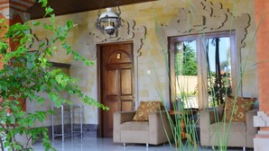 A room with a wooden door marked with the number 2, a sofa with floral cushions, and a hanging light fixture. - Puri Anom Guest House (Denpasar)