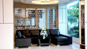 A modern lobby with a sectional sofa, a coffee table, and a decorative vase. - Avada hotel (Trat)