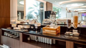 A modern breakfast bar with various food dispensers, bowls, and plates. - Avada hotel (Trat)