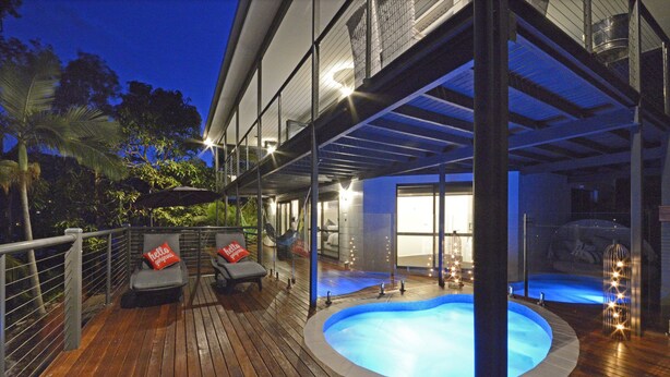 A pool area with a wooden deck, two lounge chairs, and a hot tub. - Crusoe's Beach House Ocean Views (Cannonvale)