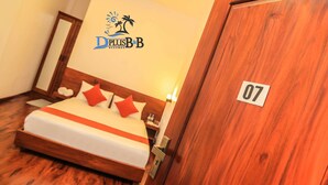 A hotel room with a bed, a wooden door with a number, and a logo on the wall. - D Plus B&B Negombo (Negombo)