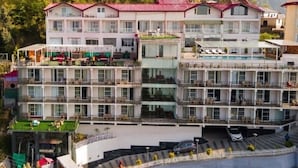 Un hotel a più piani con balconi, una terrazza sul tetto e un'area parcheggio.