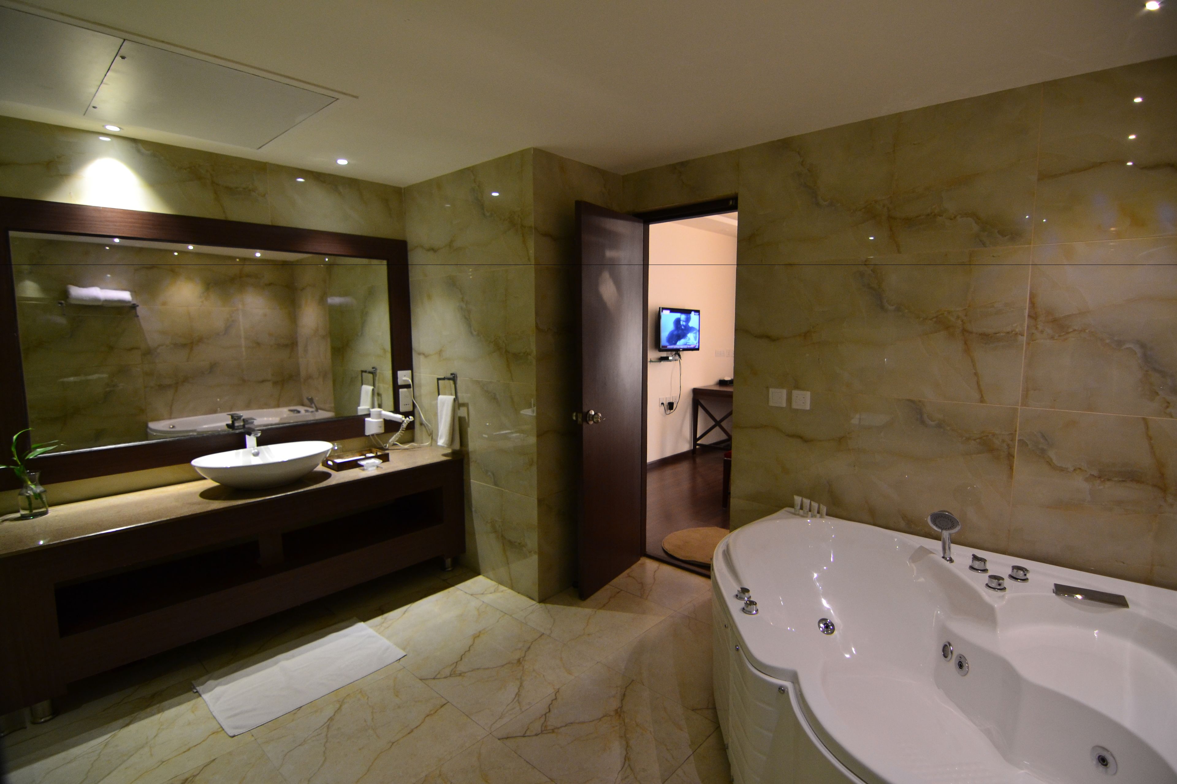 A modern bathroom with a large mirror, a sink, a bathtub, and a toilet.