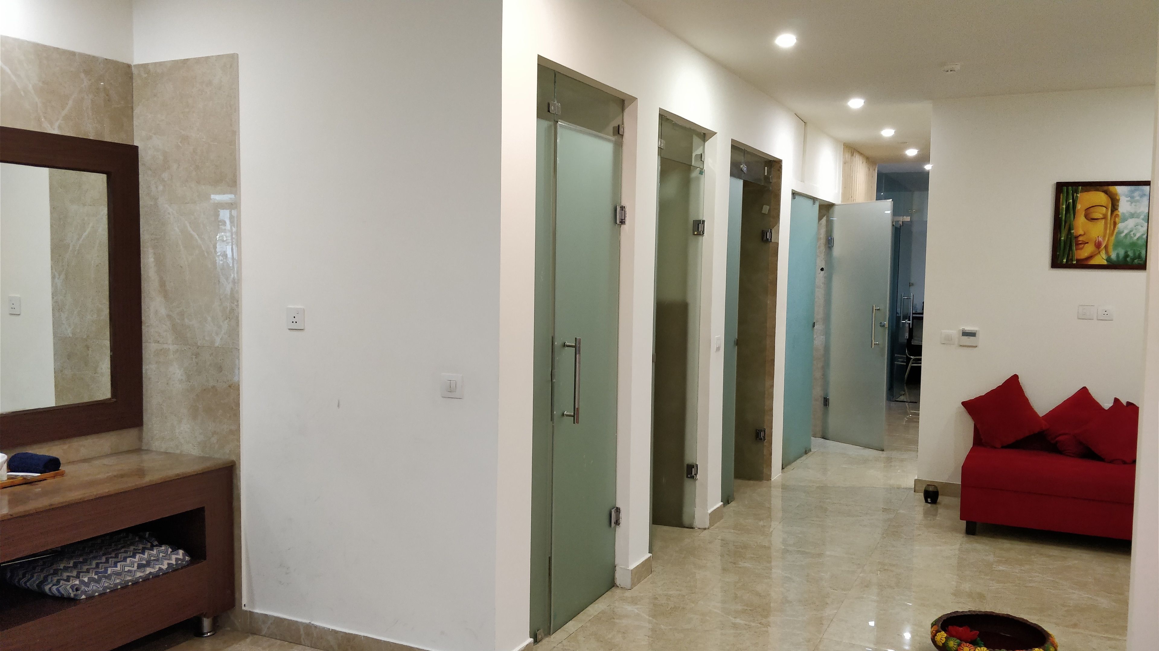 Un couloir avec un miroir, un canapé rouge et un tableau accroché au mur.