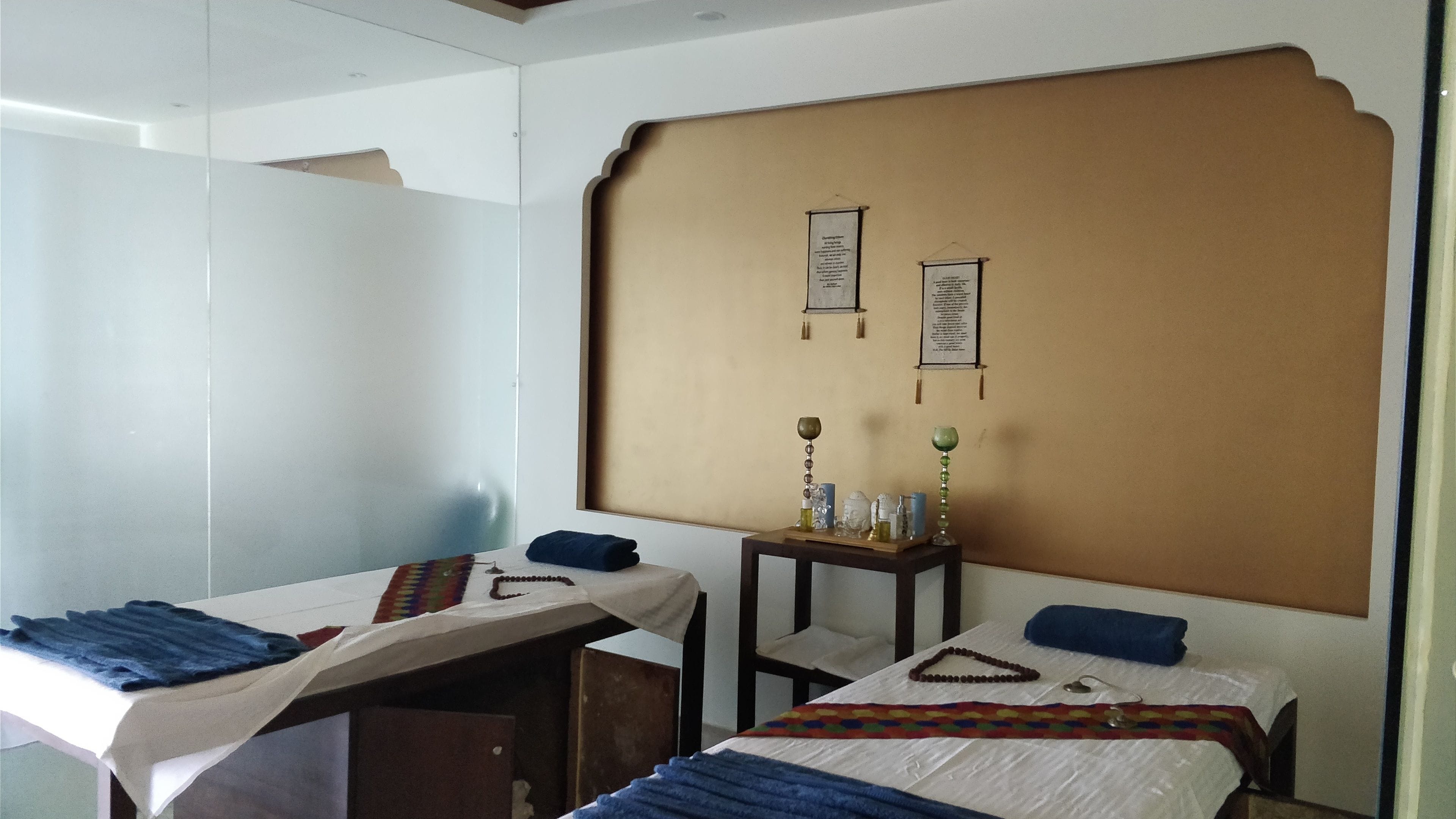 A hotel room with two beds, a small table with decorative items, and a wall with two framed notices.