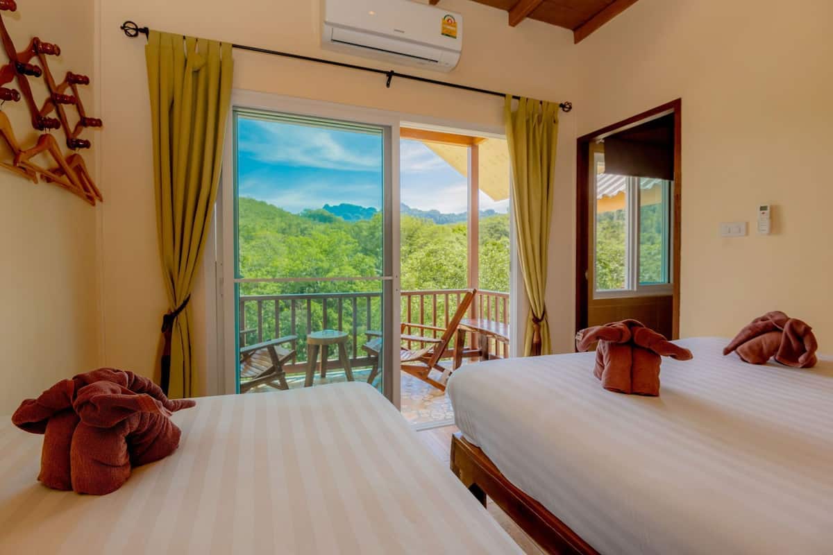 Een hotelkamer met twee bedden, een balkon met uitzicht op de bergen en een schuifdeur naar buiten.