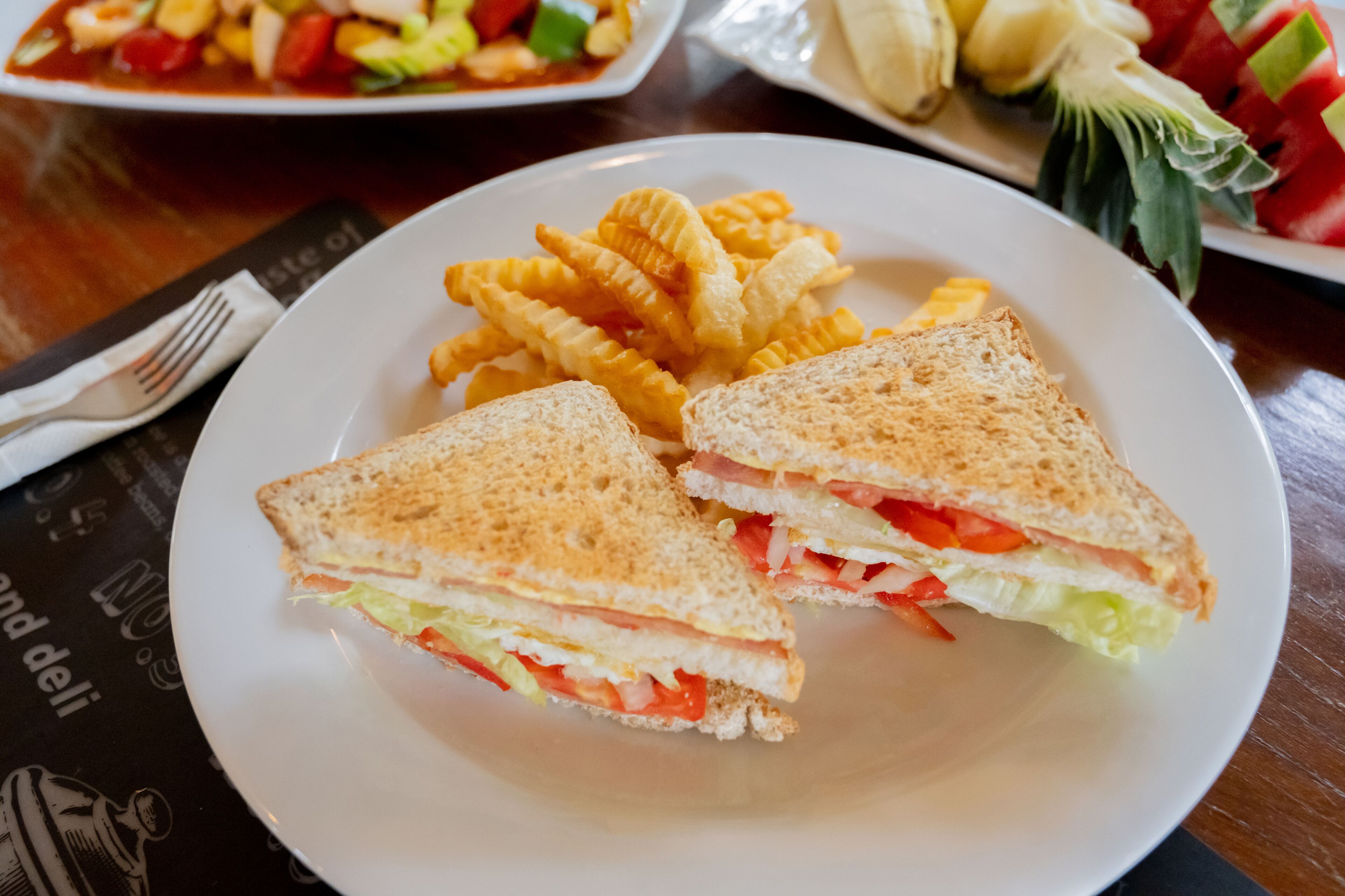 Une assiette avec un sandwich et des frites, posée sur une table.