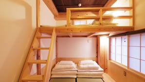 Une pièce de style japonais traditionnel, avec un sol recouvert de tatamis, un lit superposé en bois et un paravent coulissant de type shoji.