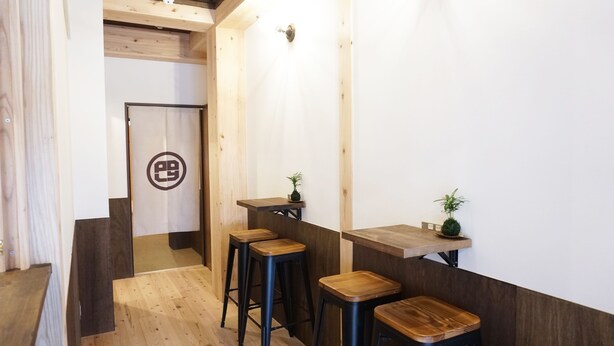 Un intérieur moderne avec un plancher en bois, un comptoir d’accueil et des tabourets de bar.