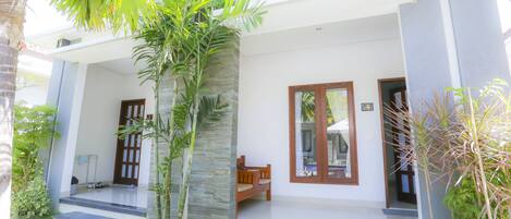 A modern house with a porch, stone pillars, and a bench.