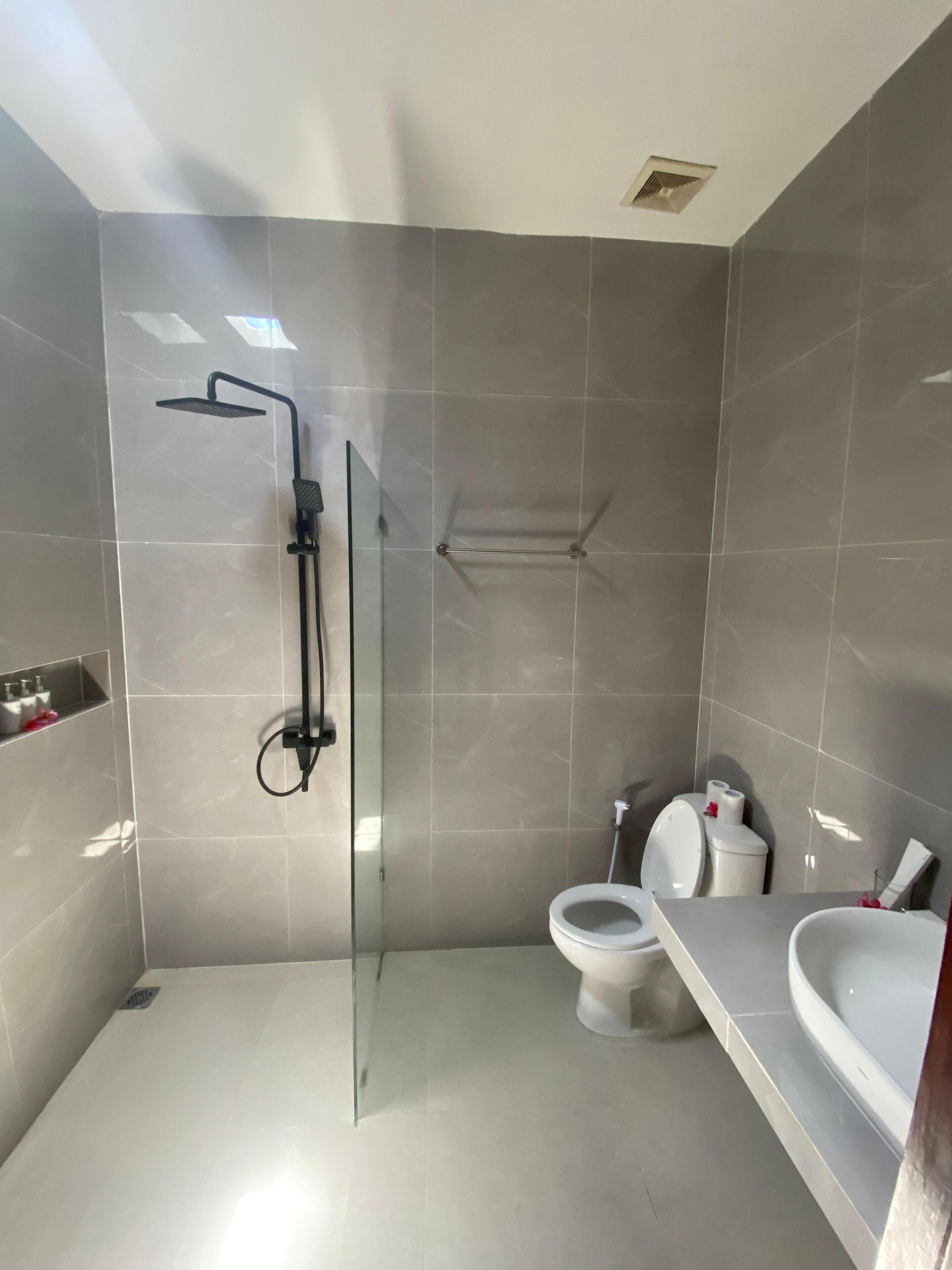 Un baño moderno con ducha de vidrio, inodoro y lavamanos.