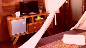 A wooden cabin room with a bed, a TV on a wooden cabinet, and a painting on the wall. - D' Padang (Pecatu)