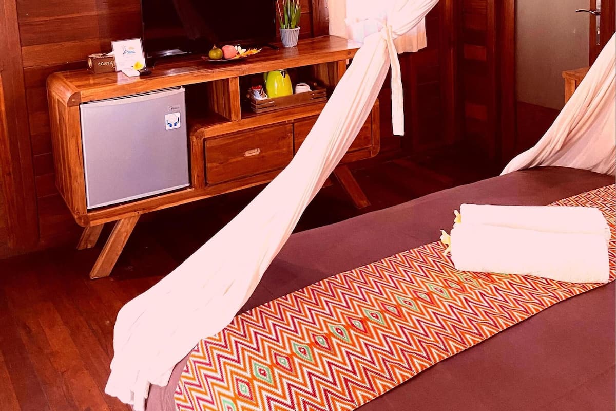 Una habitación de cabaña de madera con una cama, un televisor sobre un mueble de madera y un cuadro en la pared.