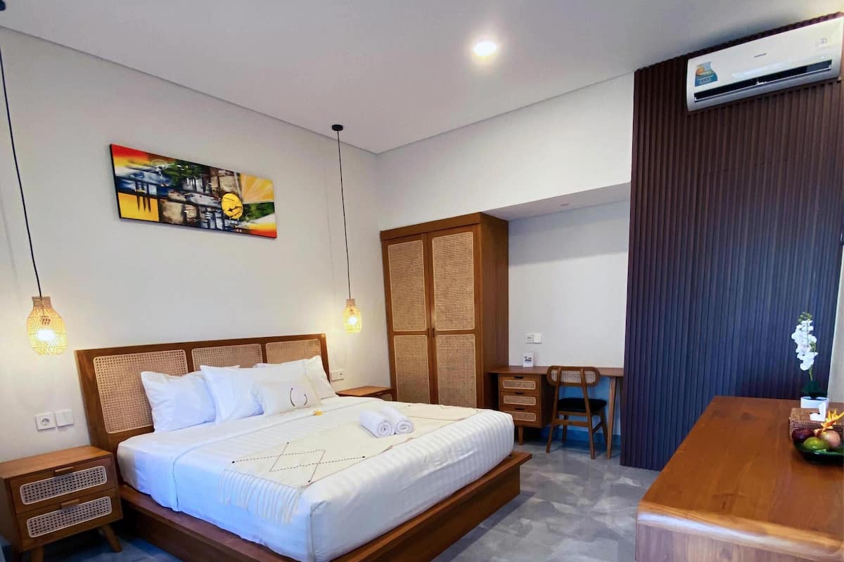 Un dormitorio moderno con una cama grande, mesitas de noche, un escritorio y un aire acondicionado.