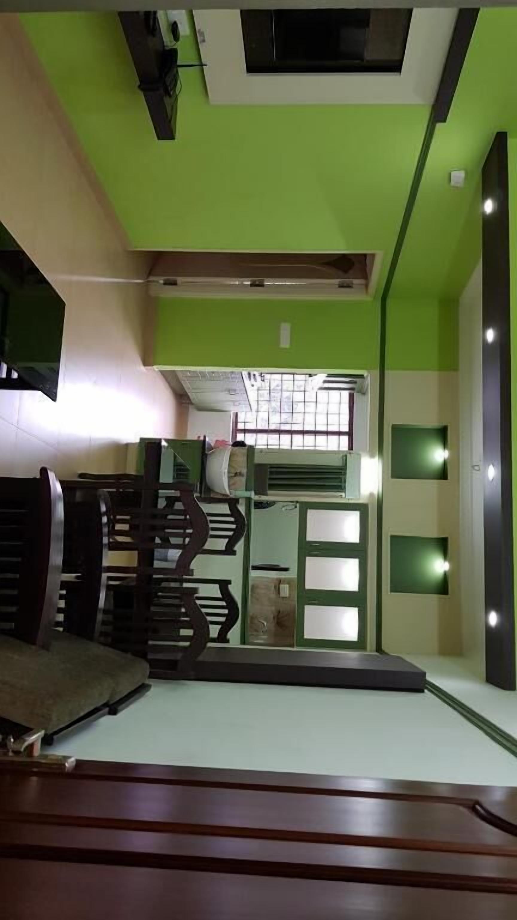 A room with a green accent wall, a staircase, and a bed.