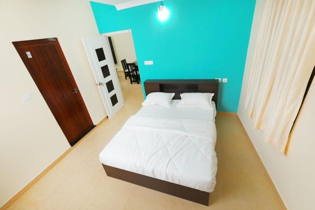 A bedroom with a bed, a door, and a wall with a light fixture.