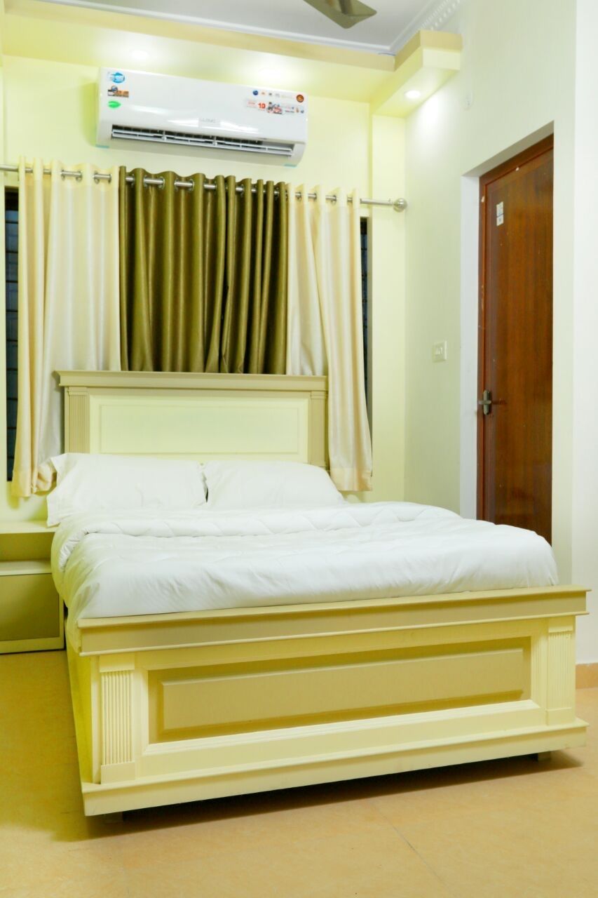 A room with a bed, an air conditioning unit, curtains, and a wooden door.