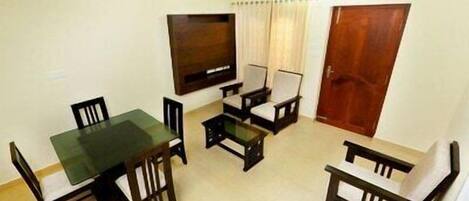 A dining area with a table and four chairs, a ceiling fan, and a door.