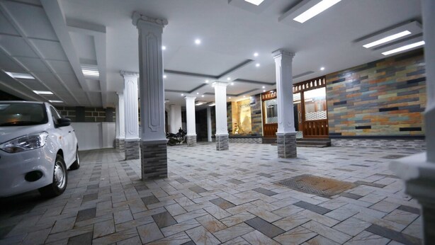 A spacious lobby with a tiled floor, white columns, and a modern ceiling design. - Shalom Residency (Kanayannur)