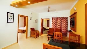A living room with a sofa, chairs, a dining table, and a TV. - Shalom Residency (Kanayannur)